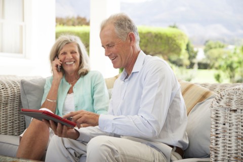 Caucasian couple using cell phone and digital tablet on sofa