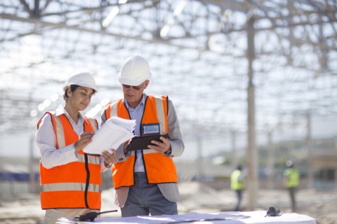 Architects reading blueprints at construction site