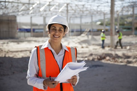 Architect holding blueprints at construction site