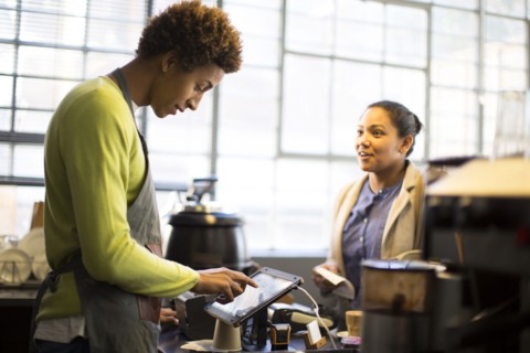 Mixed race barista assisting customer in coffee shop