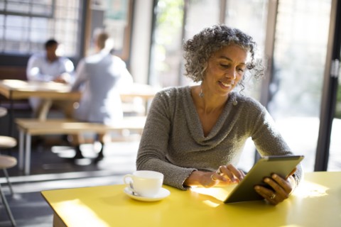 Older woman using digital tablet in cafe