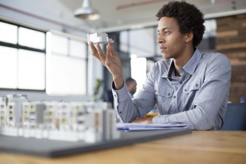 Mixed race architect examining architectural model in office