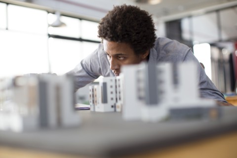 Mixed race architect examining architectural model in office