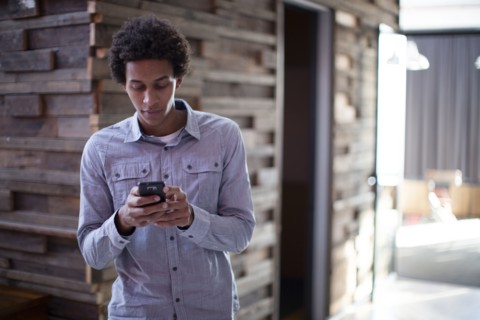 Mixed race businessman using cell phone in hallway