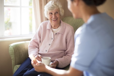 Nurse and patient drinking tea on sofa