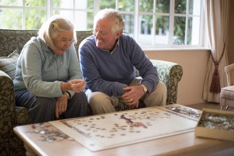 Older couple on sofa solving jigsaw puzzle