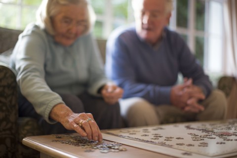 Older couple on sofa solving jigsaw puzzle
