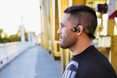 Pensive Caucasian man wearing modern headphones on bridge