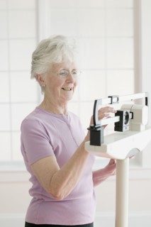 Senior woman weighing self on scale