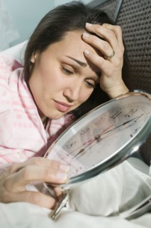 Woman laying in bed with giant alarm clock