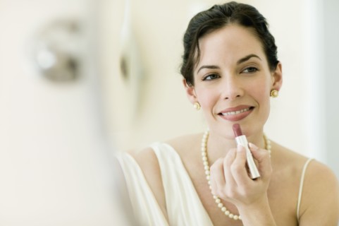 Woman in fancy clothing applying lipstick