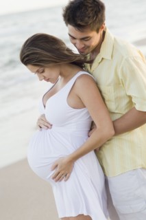 Husband hugging pregnant wife on beach