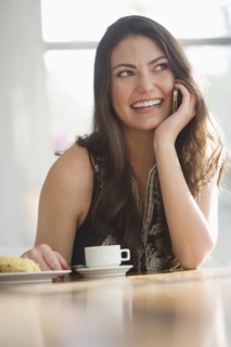 Hispanic woman drinking coffee and talking on cell phone