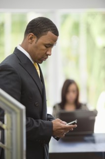 Mixed race businessman text messaging on cell phone