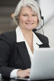 Smiling Businesswoman in headset typing on laptop