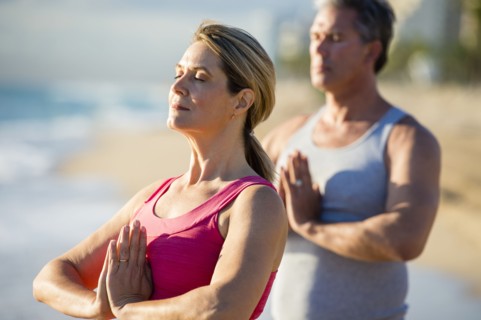 Caucasian couple meditating on beach