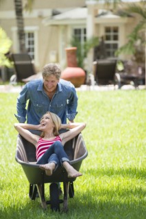 Caucasian man pushing girlfriend in wheelbarrow