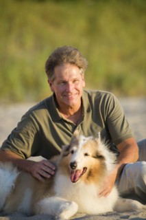 Caucasian man sitting with dog on beach