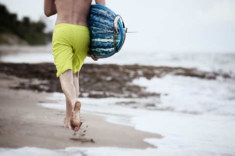 Hispanic man carrying surfboard on beach