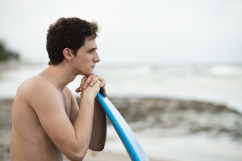 Hispanic man with surfboard on beach