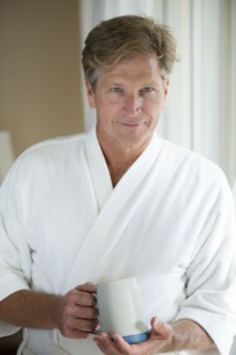 Caucasian man having coffee in bathrobe