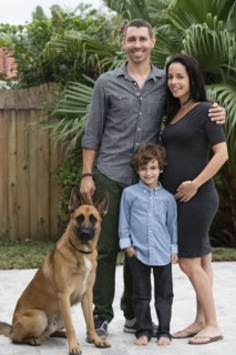 Family smiling together with dog outdoors