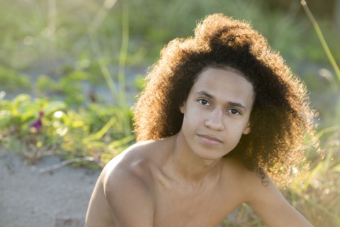 Mixed race teenage boy sitting on beach