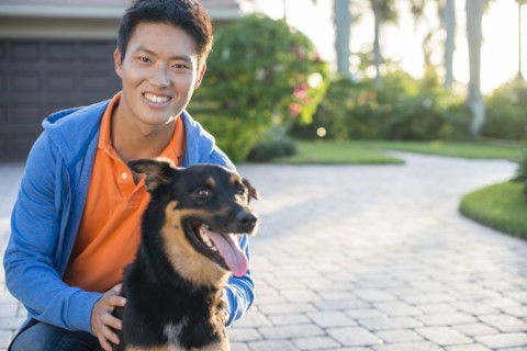Korean man holding dog in driveway