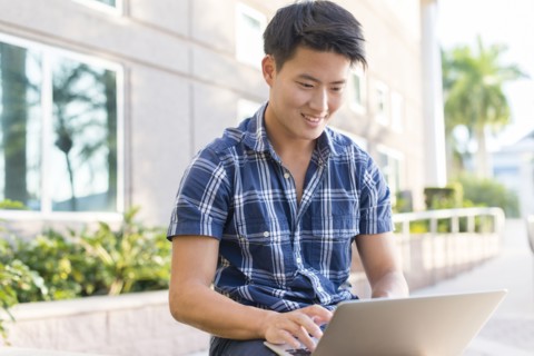 Korean man using laptop outside building