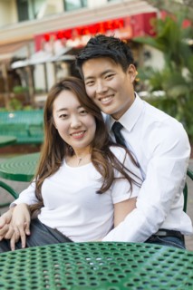 Korean couple hugging at sidewalk cafe
