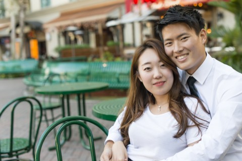 Korean couple hugging at sidewalk cafe