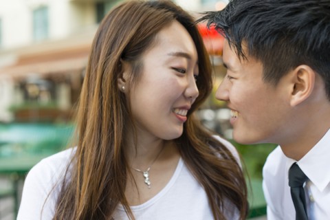 Korean couple smiling at sidewalk cafe