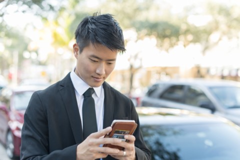 Korean businessman using cell phone outdoors