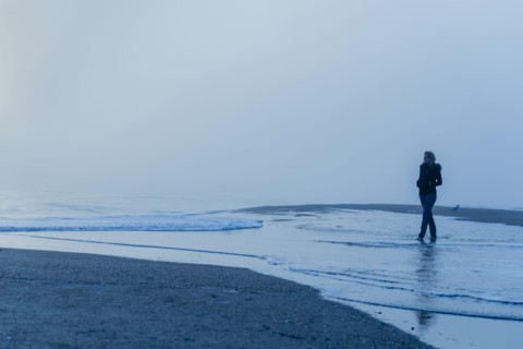 Caucasian woman walking in waves on beach