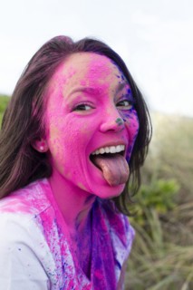 Caucasian woman splattered with paint powder with tongue out