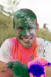 Caucasian man splattered with paint powder showing hands