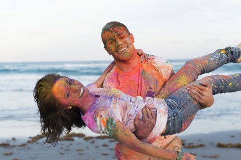 Caucasian couple splattered with paint powder on beach