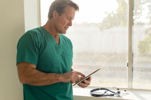 Caucasian nurse using digital tablet near window