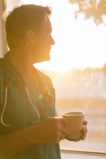 Caucasian nurse drinking cup of coffee at window