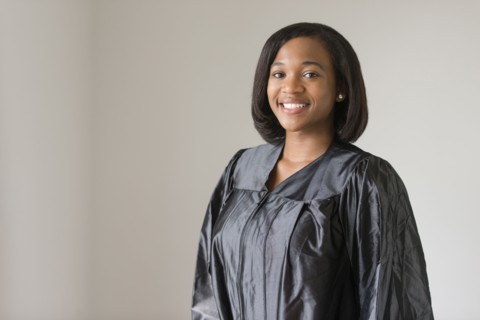 Mixed race graduate smiling in graduation robe