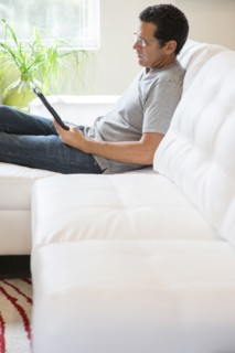 Hispanic man using digital tablet on sofa
