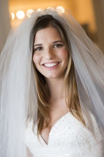 Caucasian bride smiling in wedding gown and veil