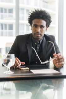 Hispanic businessman using cell phone at conference table