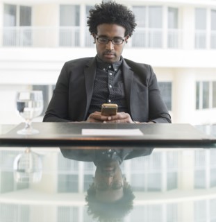 Hispanic businessman using cell phone at conference table