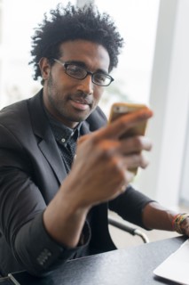 Hispanic businessman using cell phone in office