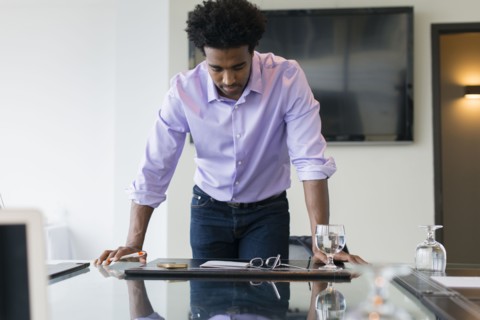 Hispanic businessman leaning over conference table