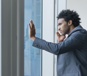 Hispanic businessman talking on cell phone at office window