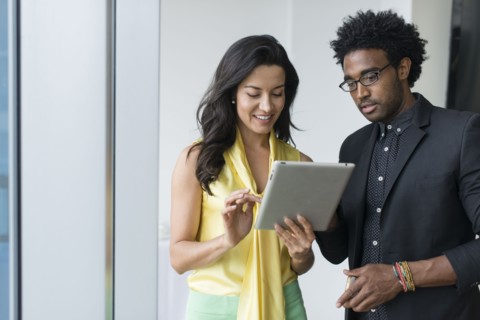 Hispanic business people using digital tablet in office