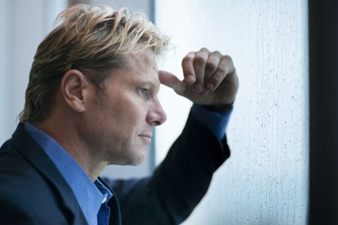 Caucasian businessman standing at rainy office window