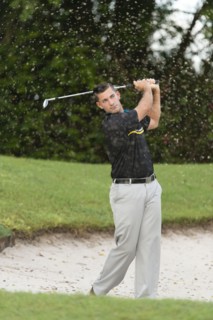 Caucasian man chipping from golf course sand trap